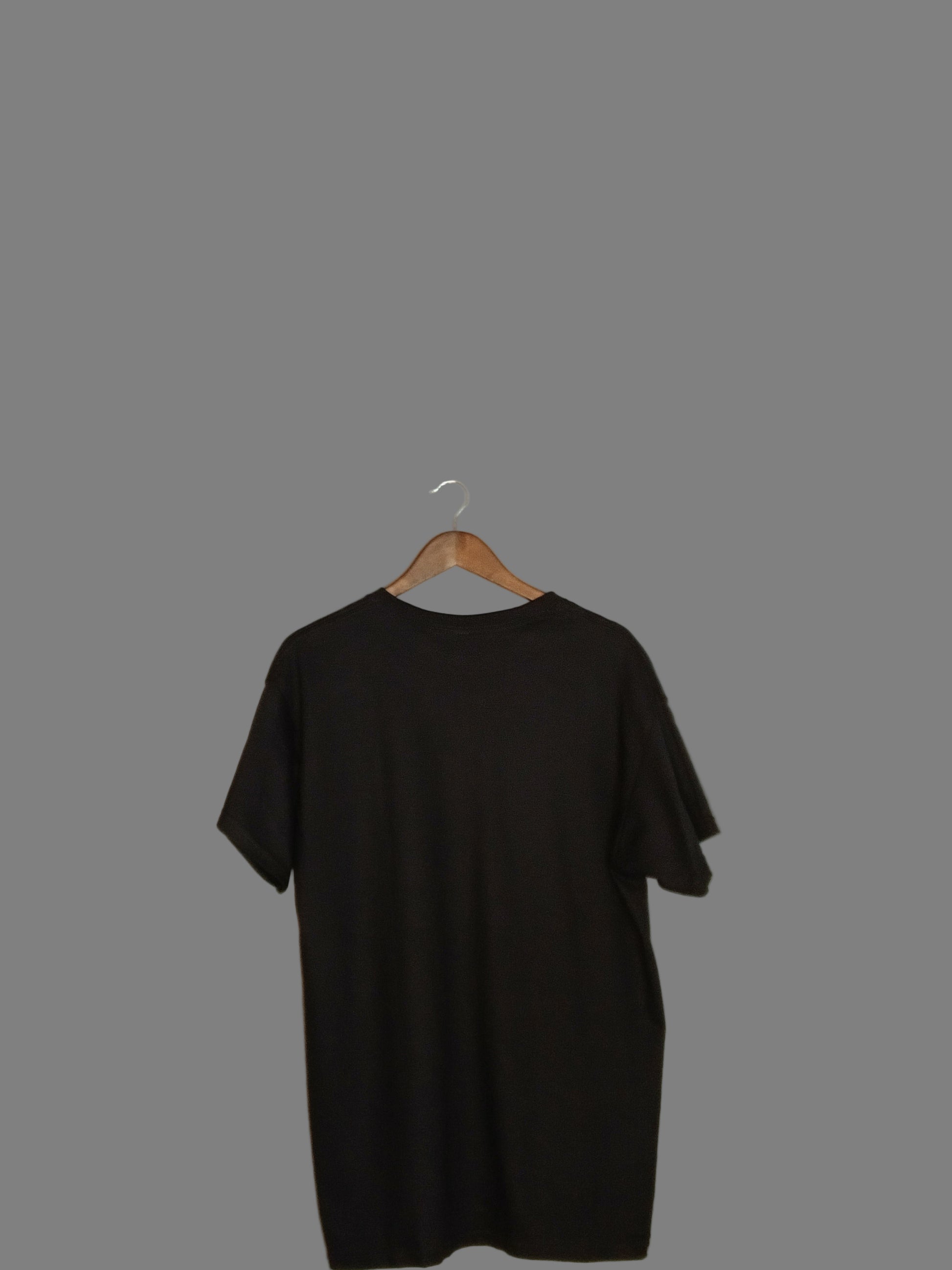 Black dress on a hanger against a plain wall back view