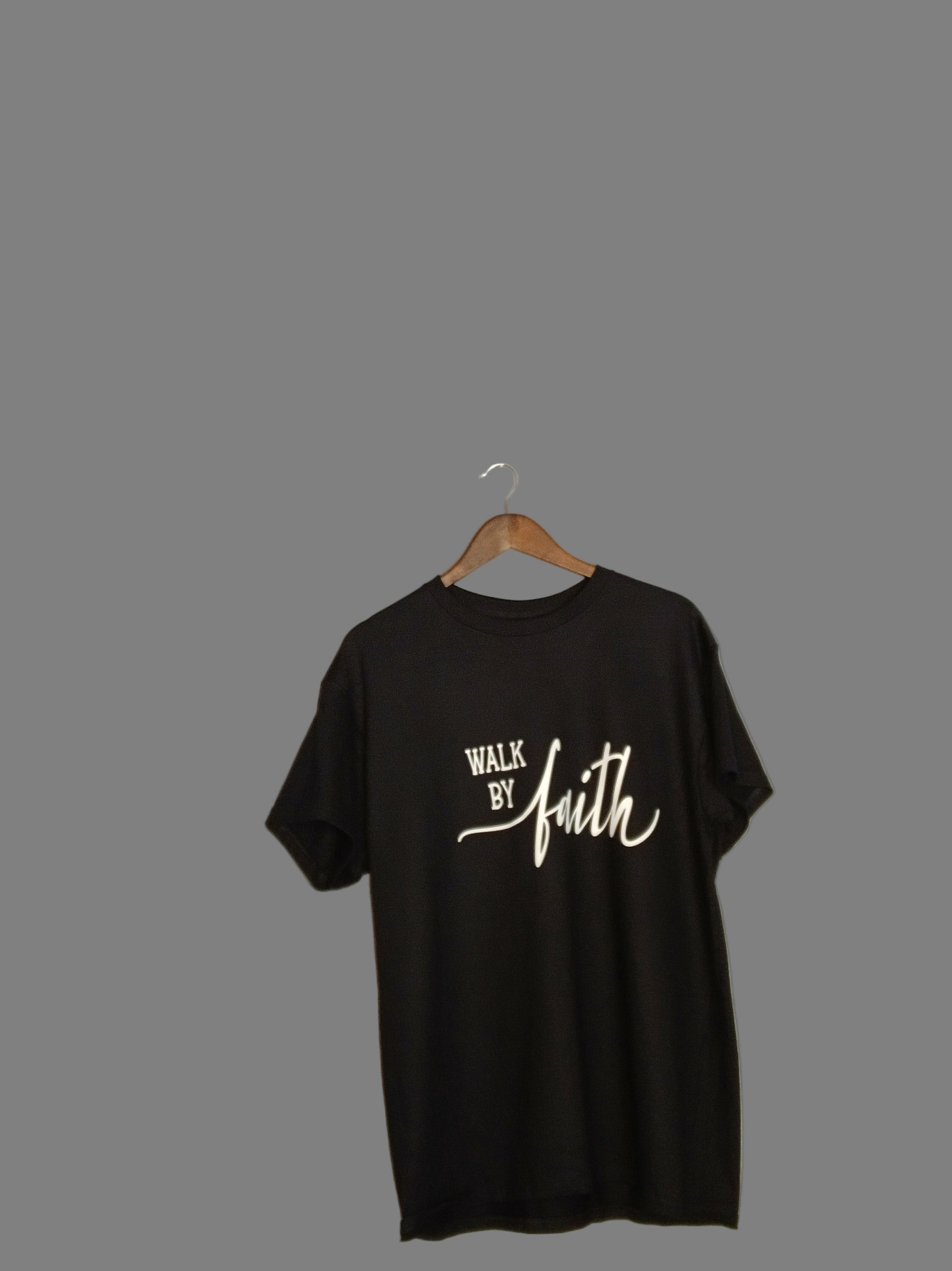 Black sleeveless shirt with white text on a hanger against a plain wall.