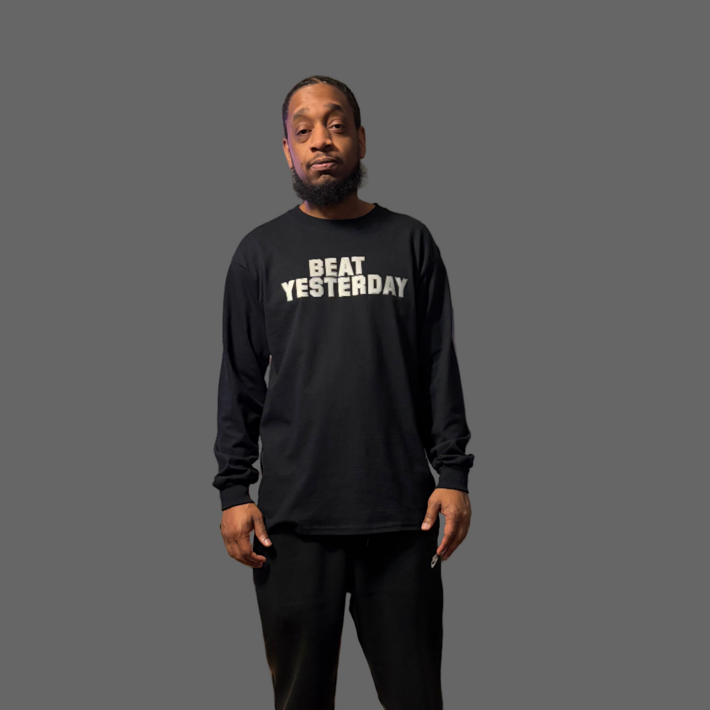 Man wearing a black sweatshirt with 'Beat Yesterday' text in a living room with a Christmas tree.